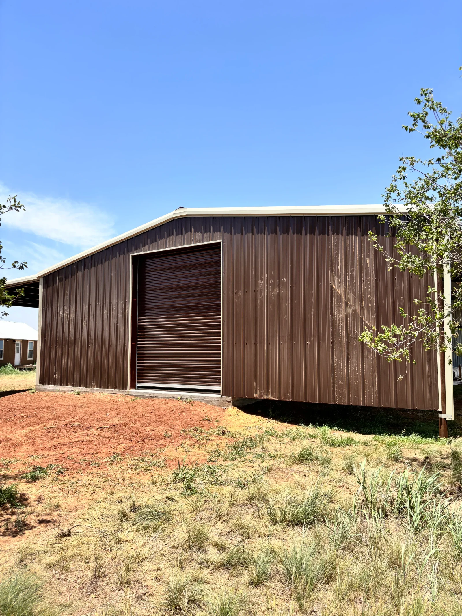 Brown corrugated metal storage building with roll-up door and curved roof